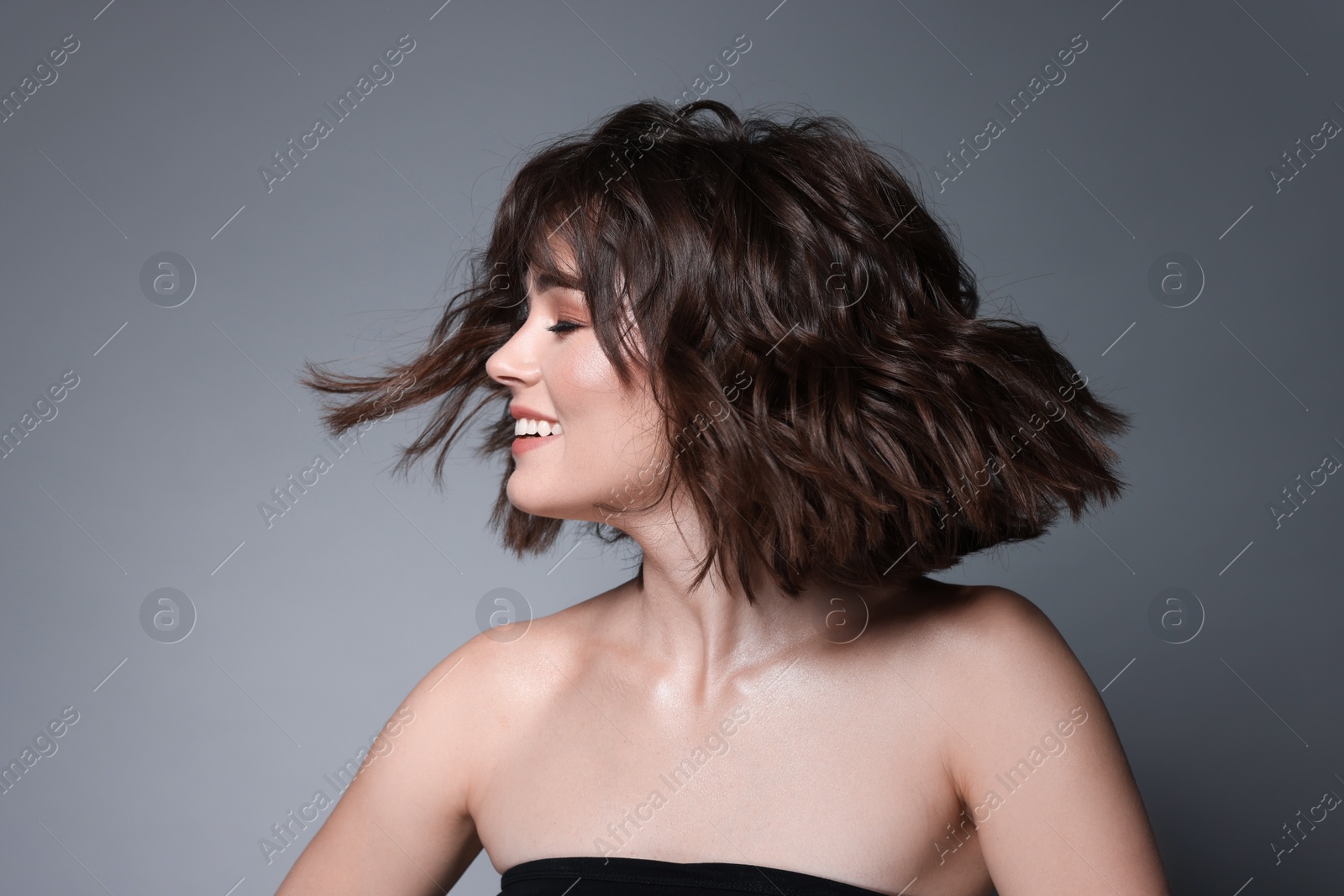 Photo of Portrait of beautiful young woman with wavy hairstyle on grey background