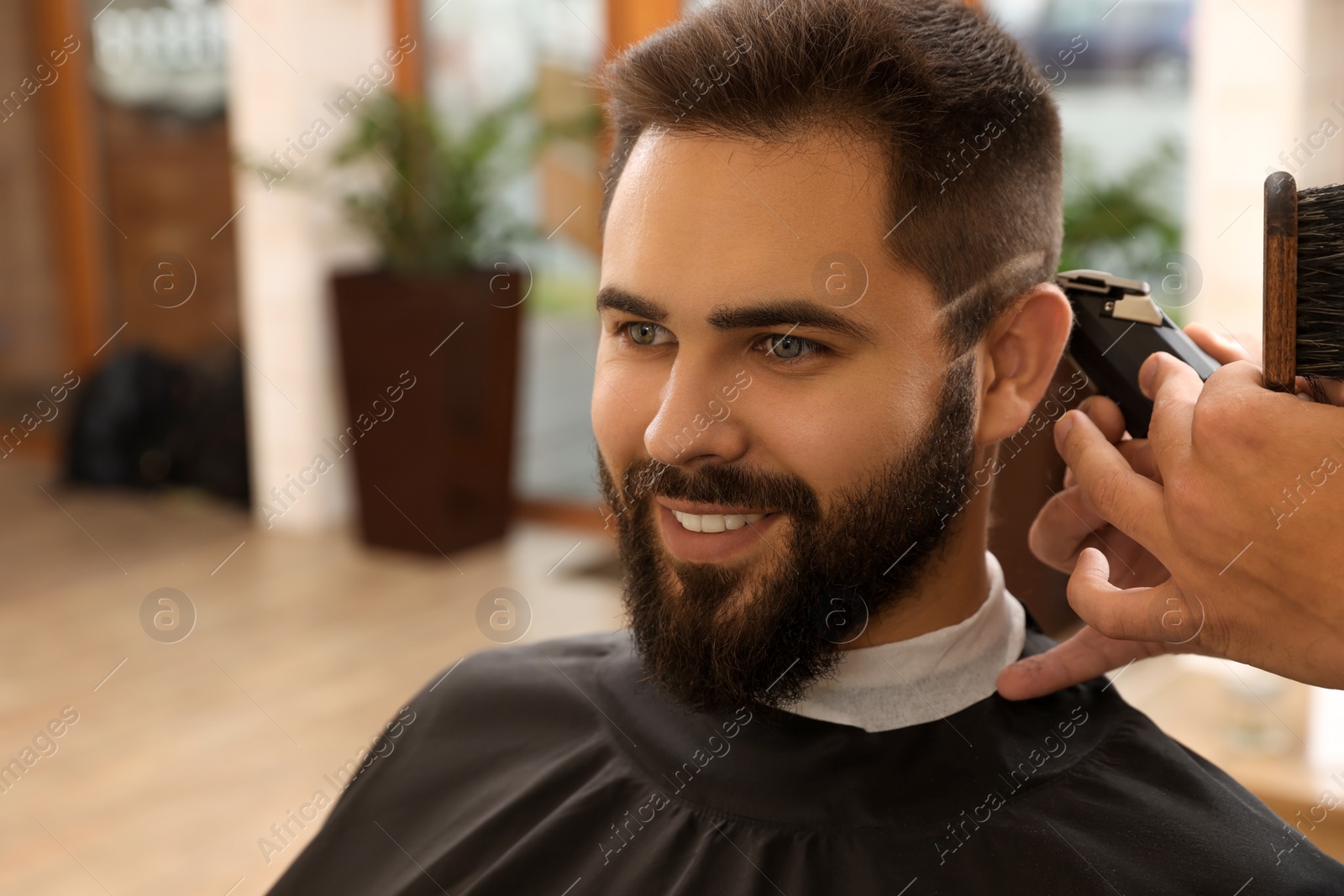 Photo of Professional hairdresser working with client in barbershop, closeup