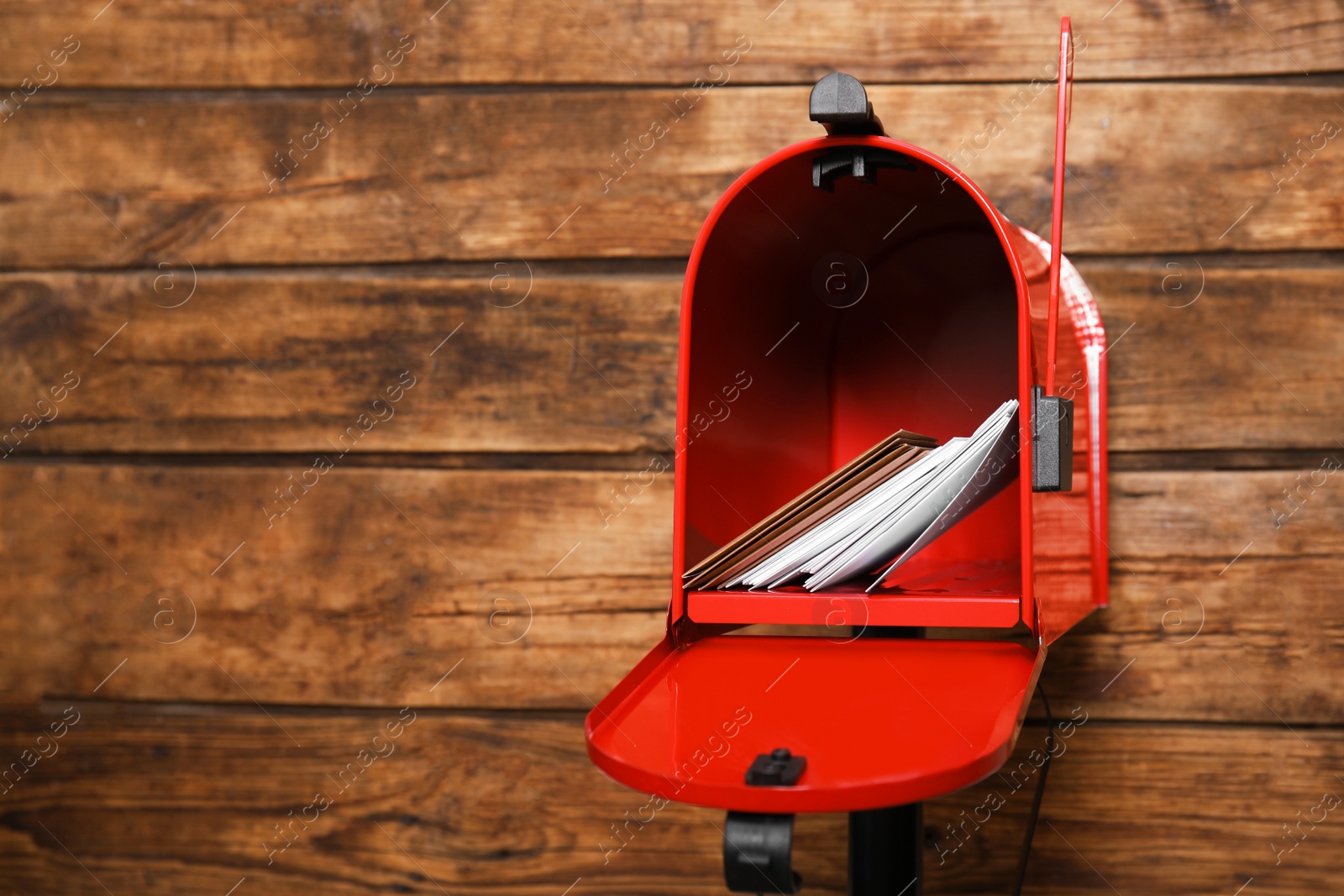 Photo of Open red letter box with envelopes against wooden background. Space for text