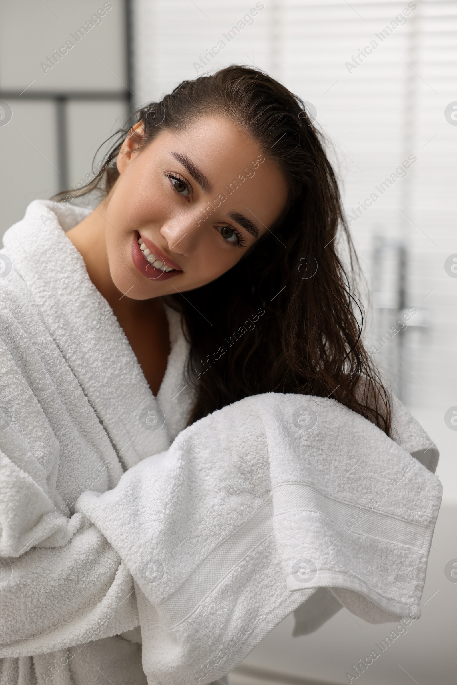 Photo of Smiling woman drying hair with towel after shower in bathroom