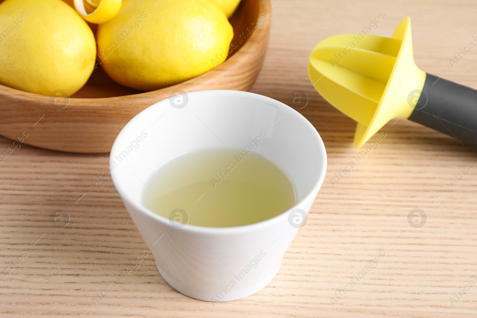 Photo of Freshly squeezed lemon juice and reamer on wooden table