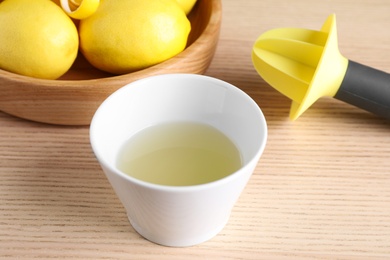 Freshly squeezed lemon juice and reamer on wooden table
