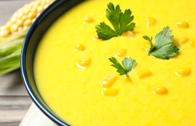 Delicious creamy corn soup with parsley in bowl, closeup