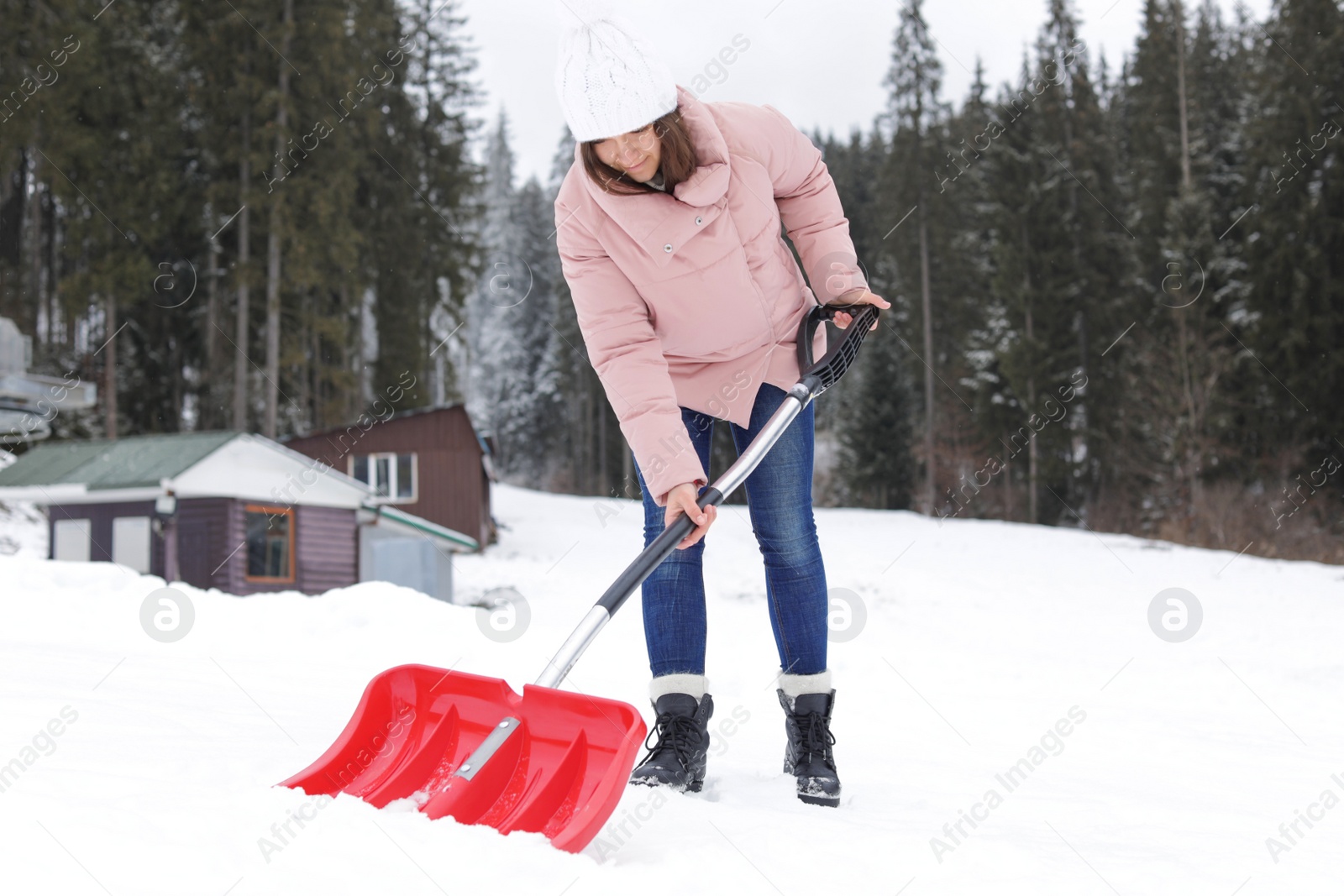 Photo of Woman removing snow with shovel near house