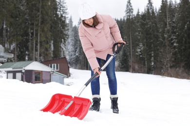 Photo of Woman removing snow with shovel near house