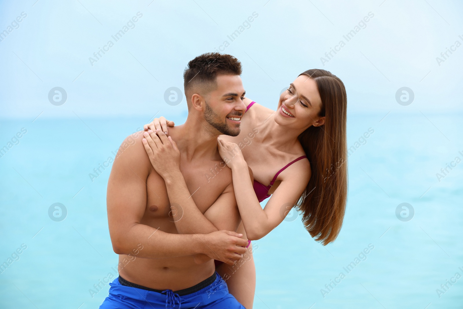 Photo of Young woman in bikini with her boyfriend on beach. Lovely couple