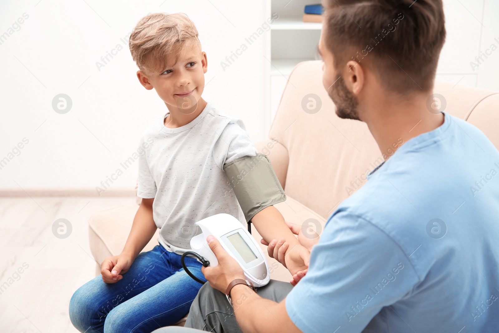 Photo of Young man checking little boy's pulse indoors