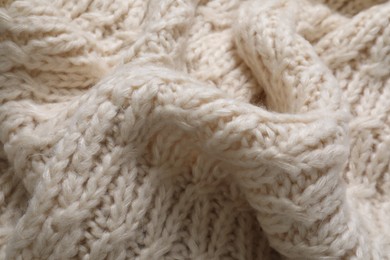 Photo of Beige knitted scarf as background, closeup view