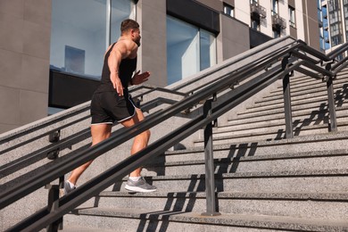 Photo of Man running up stairs outdoors on sunny day