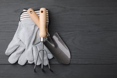 Photo of Gardening gloves, trowel and rake on grey wooden table, top view. Space for text