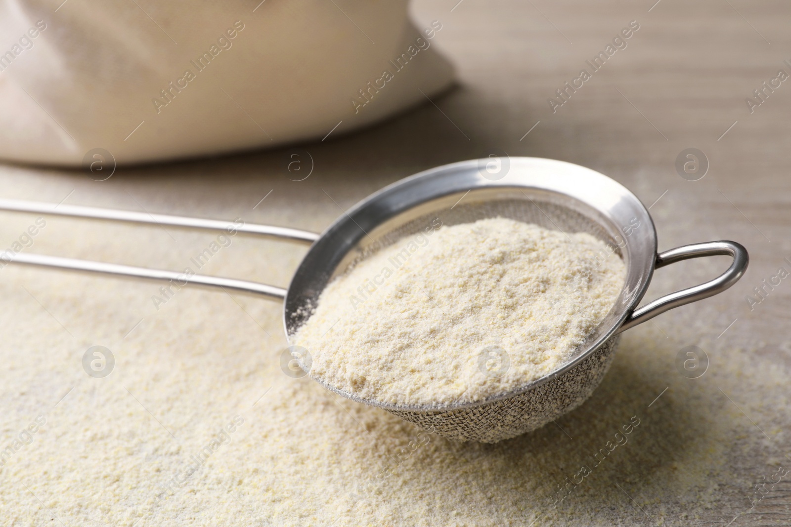 Photo of Sieve with quinoa flour on wooden table, closeup