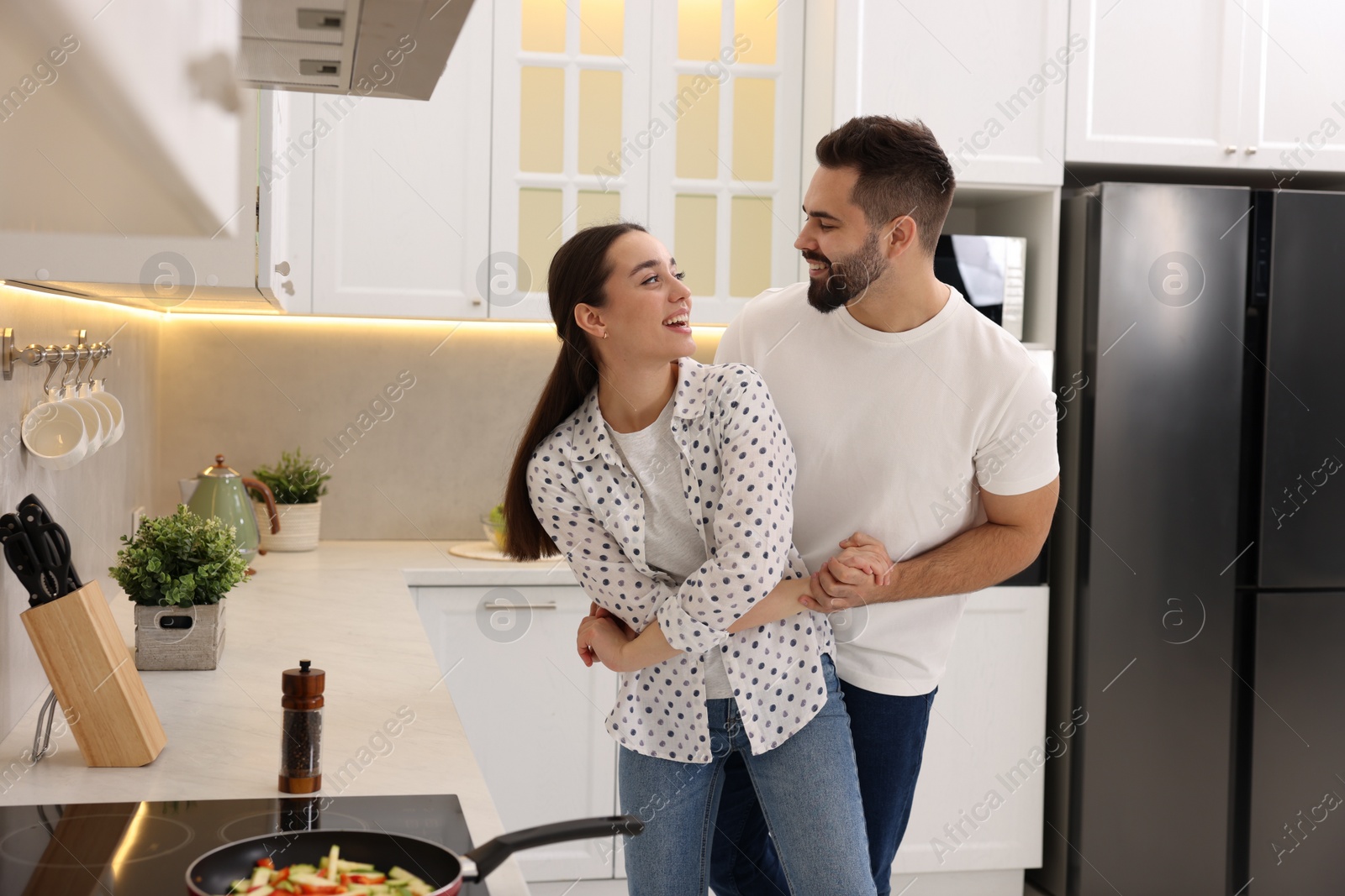 Photo of Lovely couple dancing together while cooking in kitchen