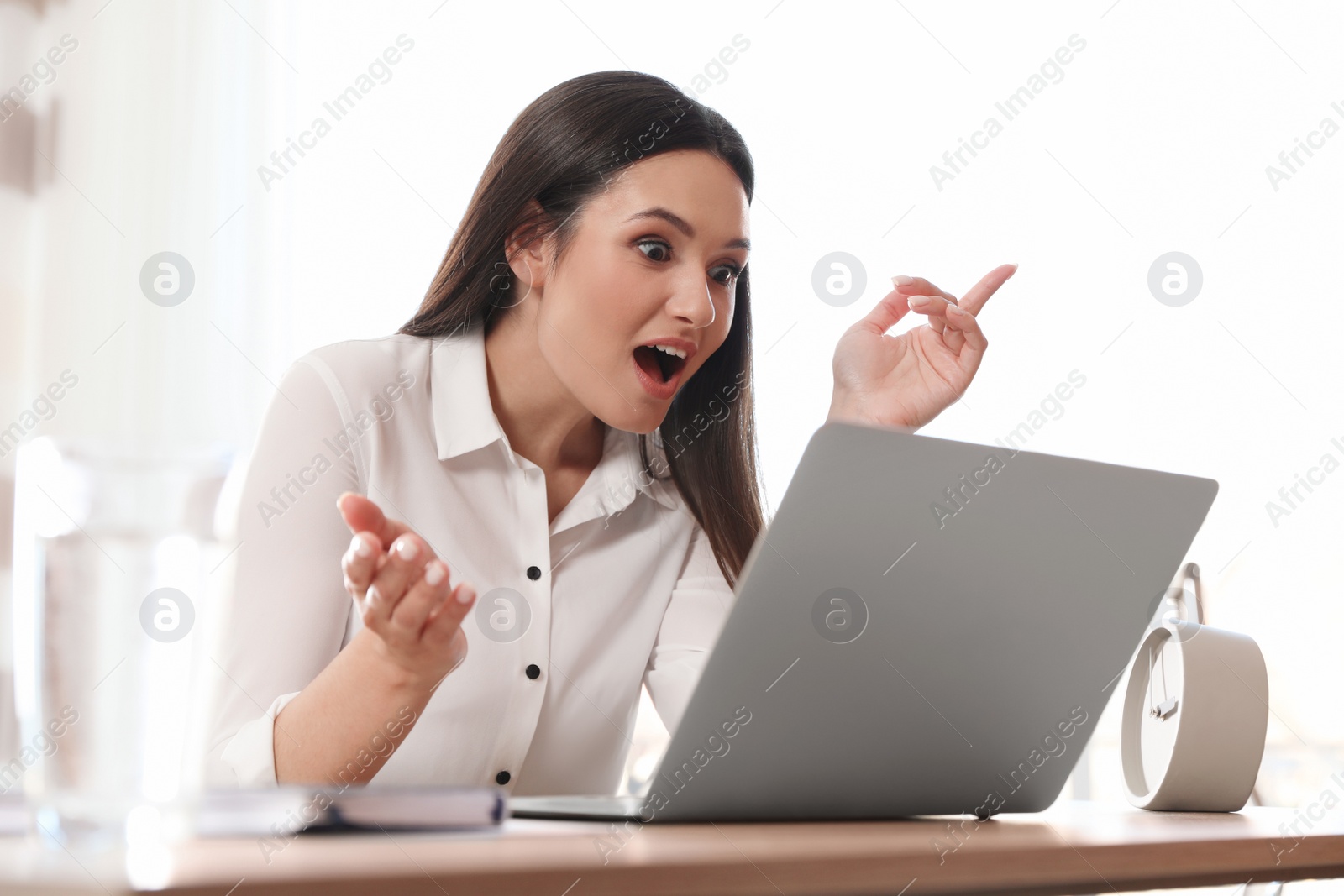 Photo of Young woman using video chat on laptop in home office