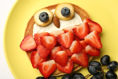 Photo of Creative serving for kids. Plate with cute owl made of pancakes, berries, cream, banana and almond on white table, top view