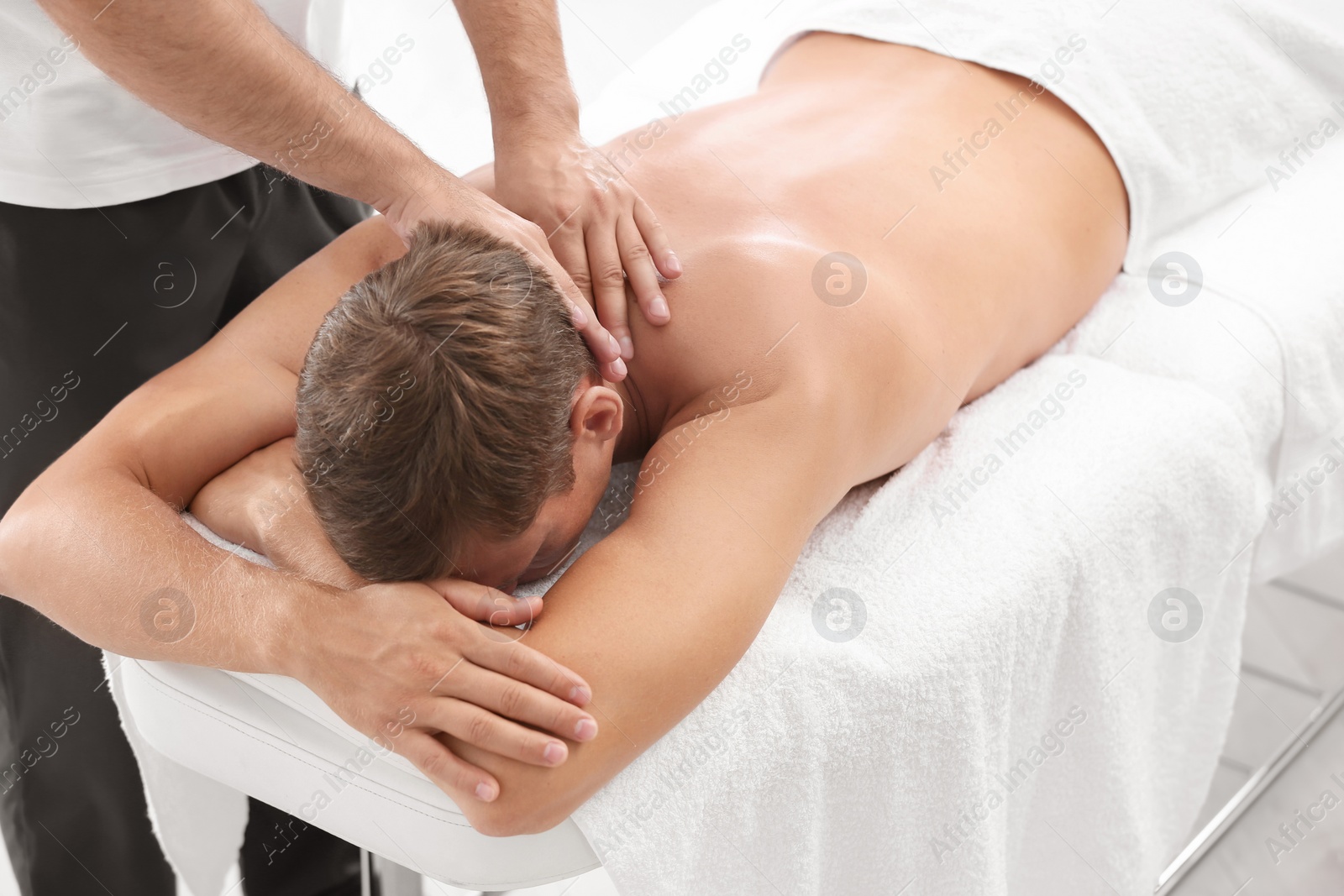 Photo of Relaxed man receiving back massage in wellness center