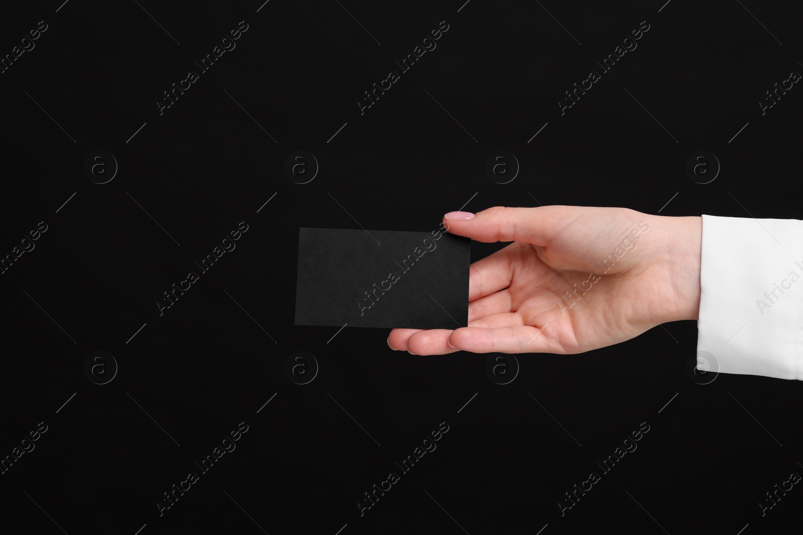 Photo of Woman holding blank business card on black background, closeup. Space for text