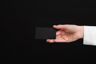 Photo of Woman holding blank business card on black background, closeup. Space for text