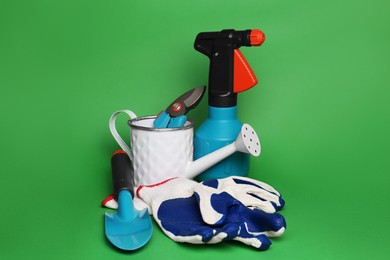 Photo of Gardening gloves, tools and watering can on green background