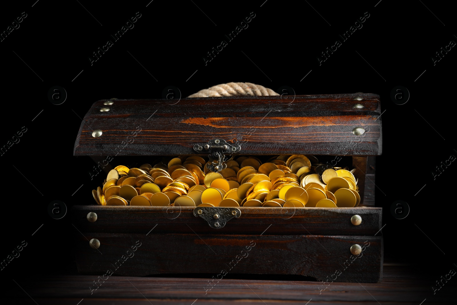 Image of Open treasure chest with gold coins on wooden table