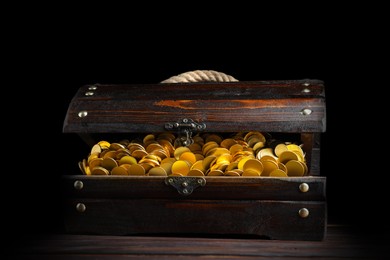 Open treasure chest with gold coins on wooden table