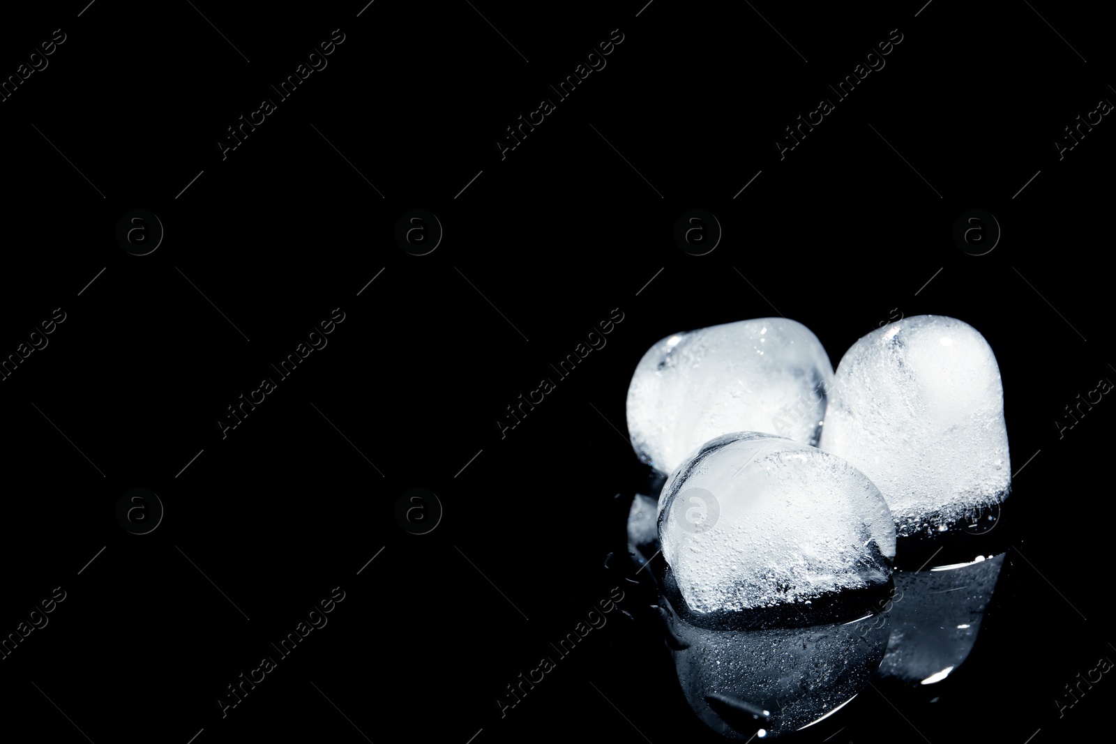 Photo of Melting ice cubes on black background. Space for text