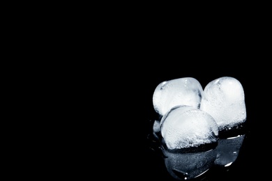 Photo of Melting ice cubes on black background. Space for text