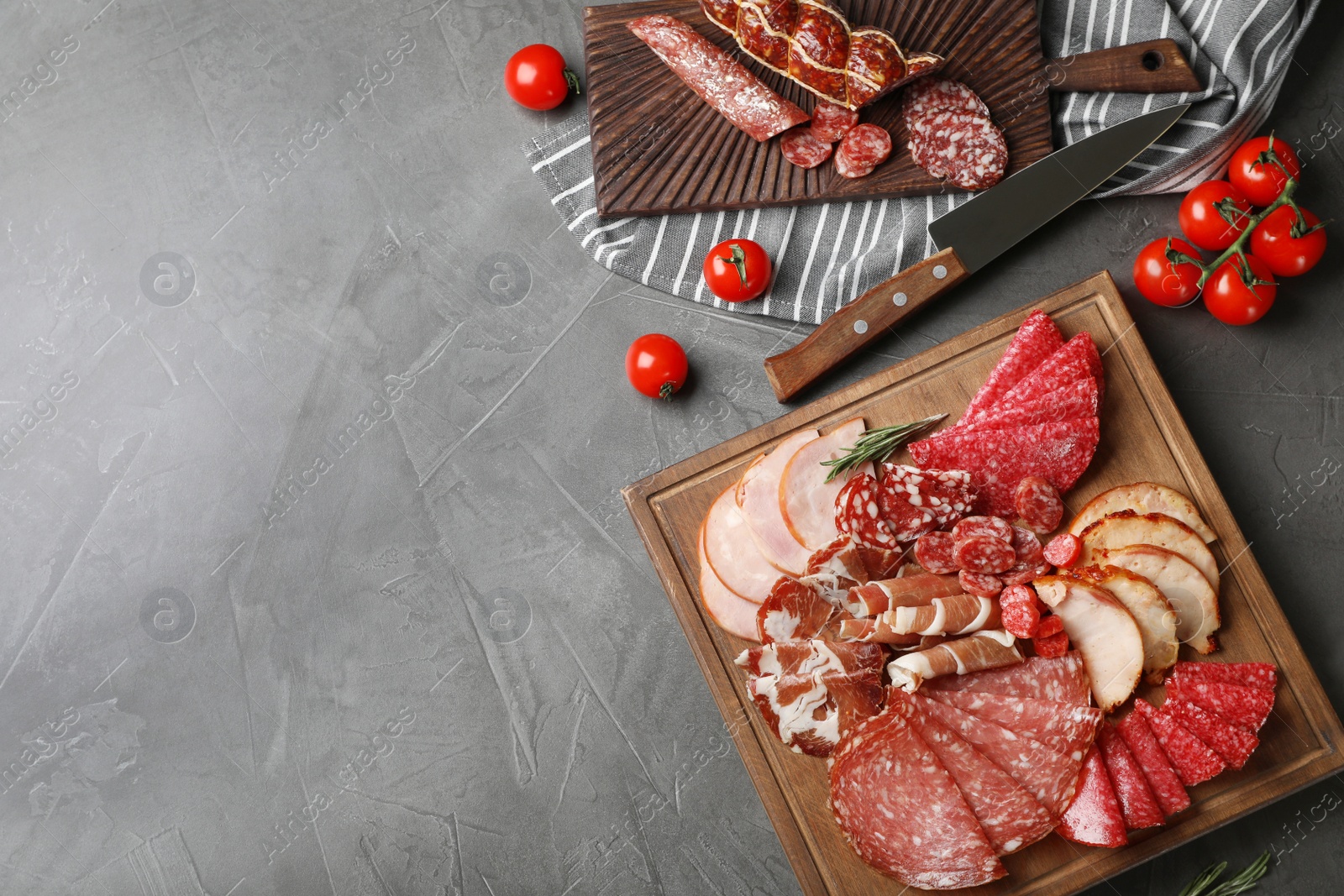 Photo of Cutting board with different sliced meat products on table, flat lay. Space for text