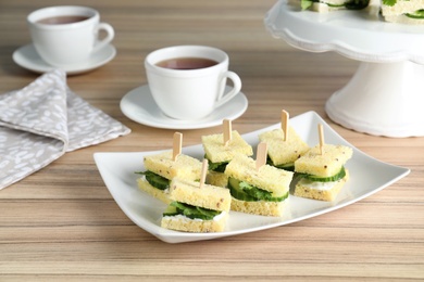 Photo of Plate with traditional English cucumber sandwiches on table