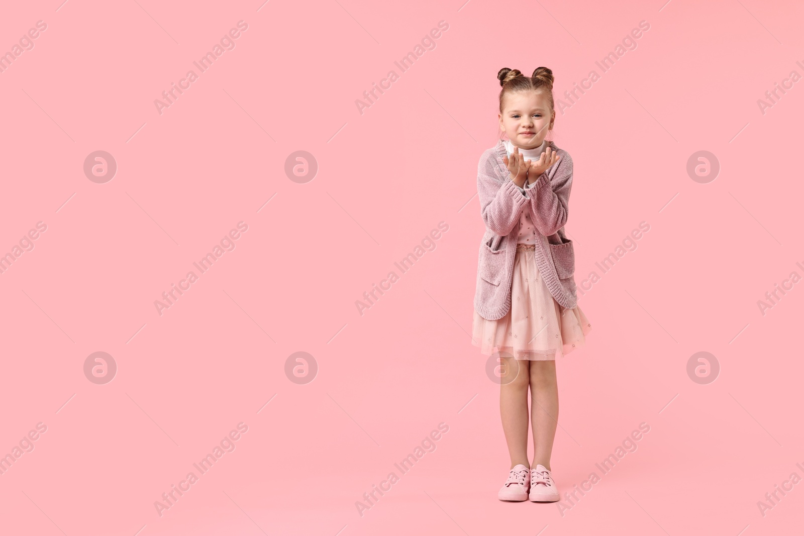 Photo of Cute little girl dancing on pink background, space for text