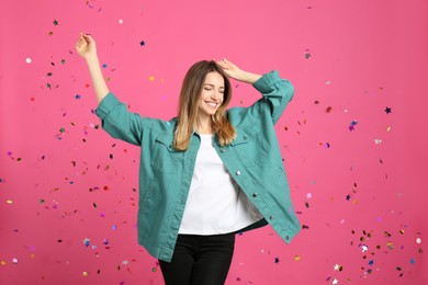 Photo of Happy woman and falling confetti on pink background