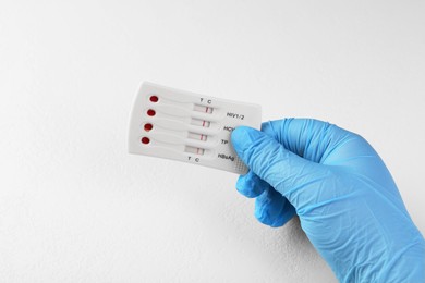 Photo of Doctor holding disposable multi-infection express test at white table, closeup
