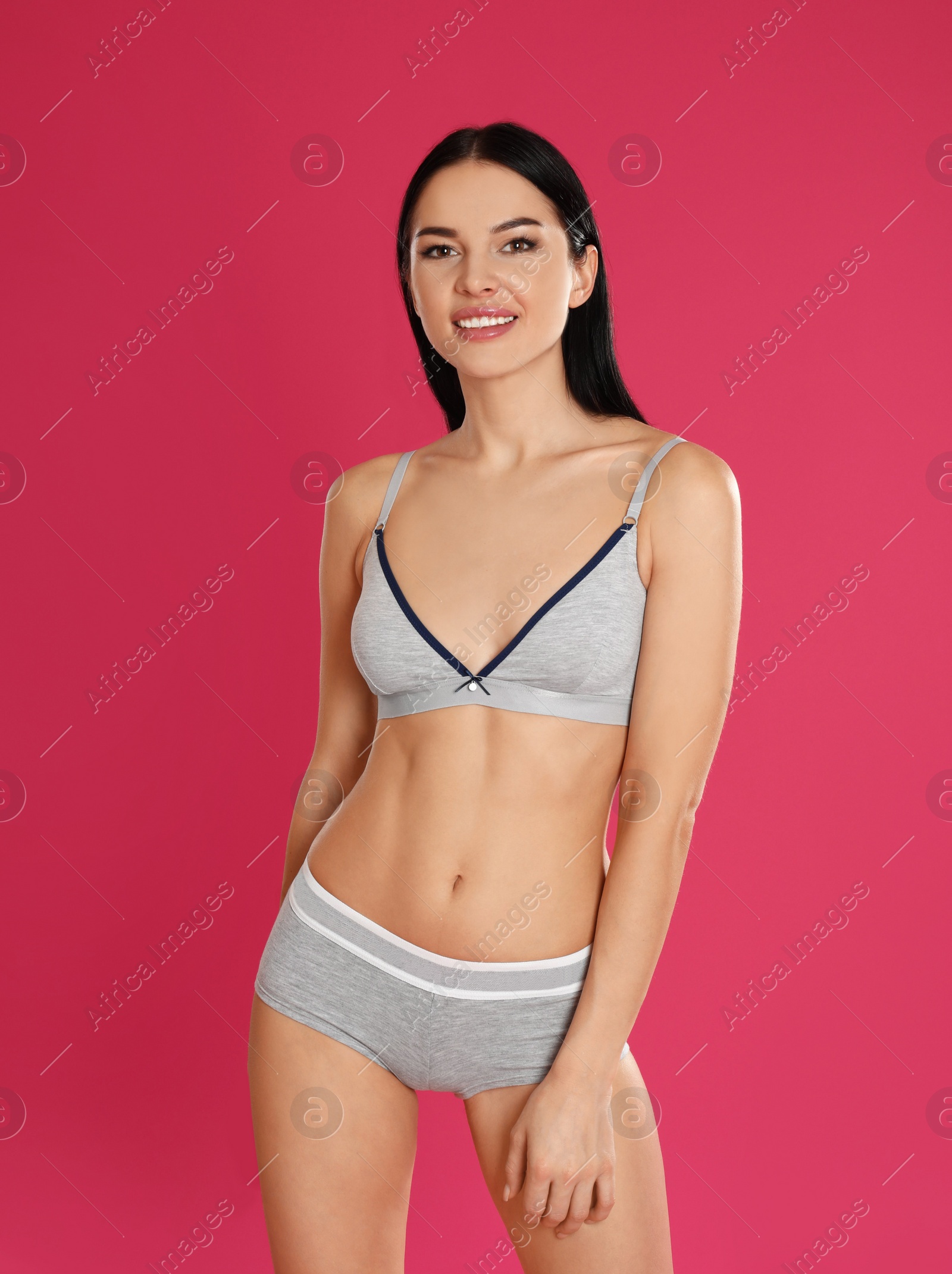 Photo of Beautiful young woman in grey sportive underwear on pink background