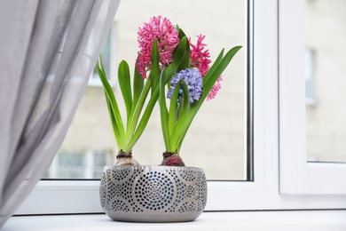 Photo of Blooming spring hyacinth flowers on windowsill at home, space for text