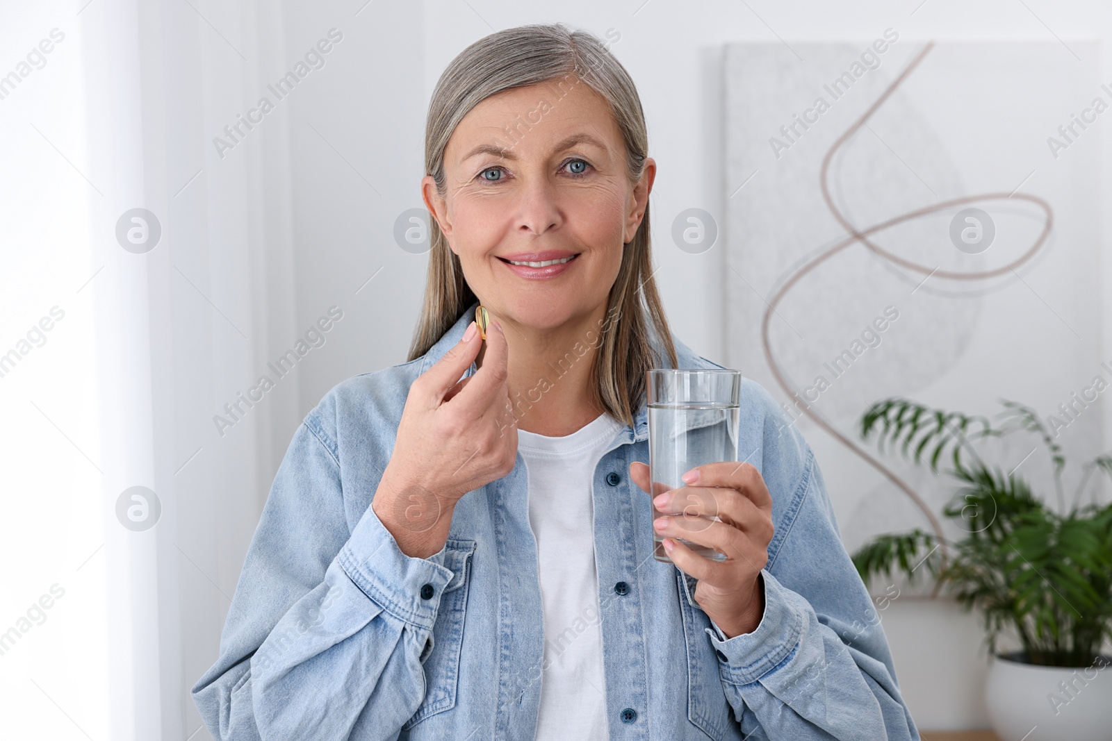 Photo of Beautiful woman taking vitamin pill at home