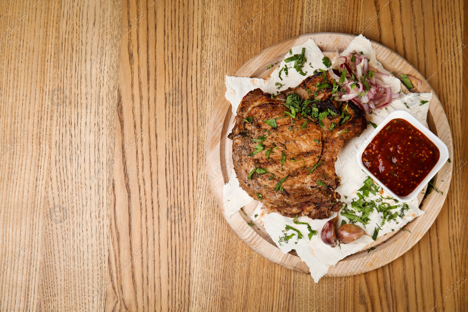 Photo of Delicious grilled pork chop served on wooden table, top view. Space for text