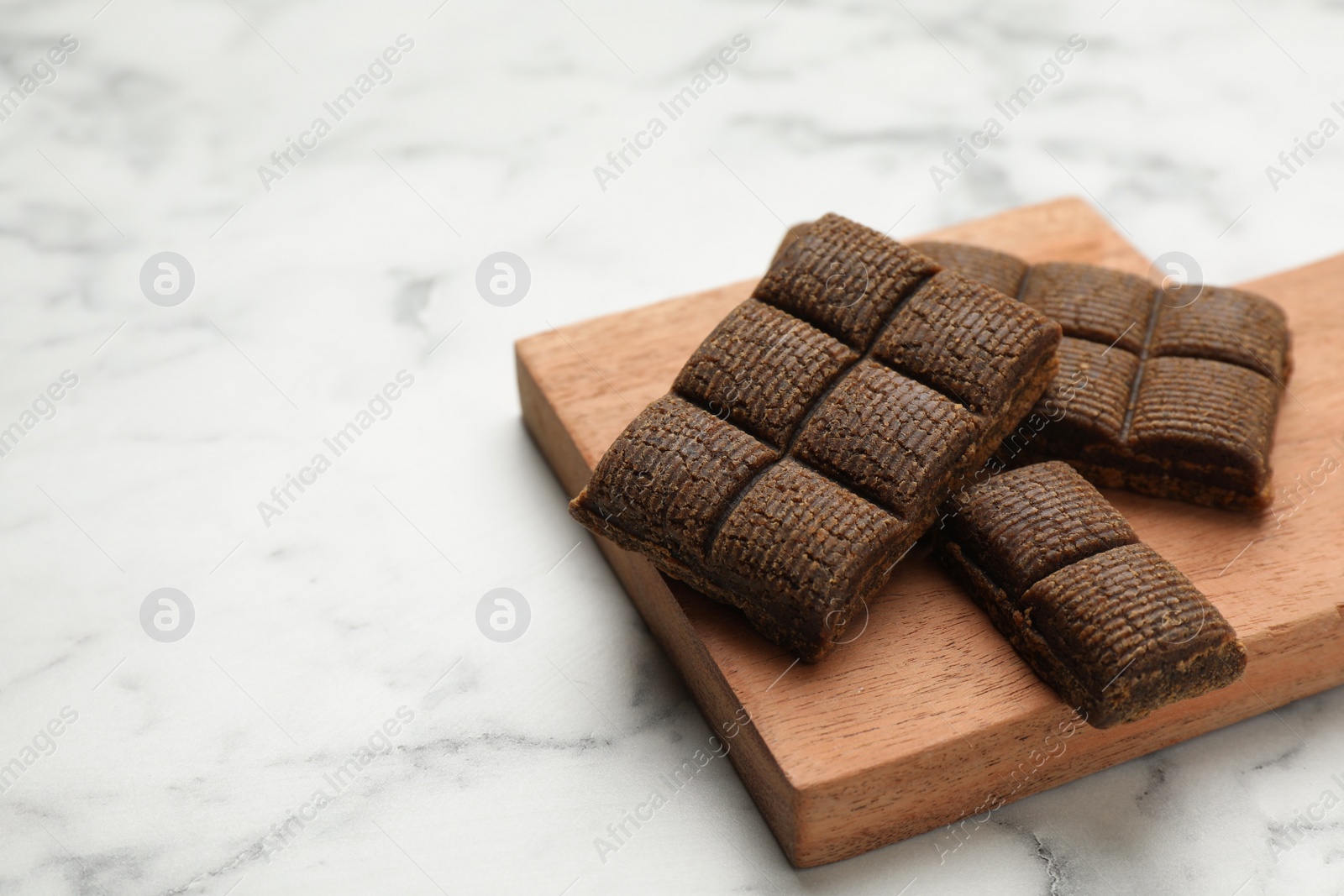 Photo of Wooden board with delicious and healthy hematogen on white marble table. Space for text