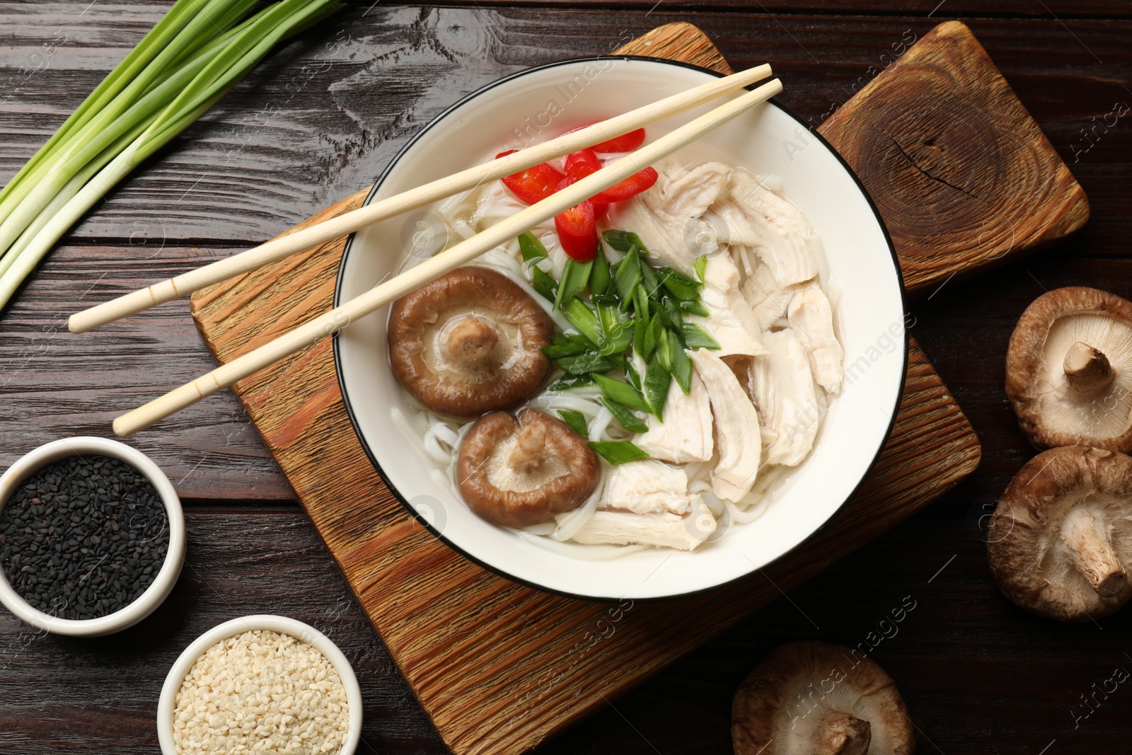 Photo of Delicious ramen with meat and ingredients on wooden table, flat lay. Noodle soup