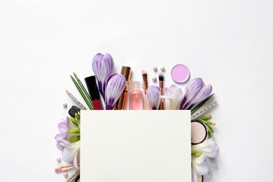 Makeup products, spring flowers and blank card on white background, top view. Space for text