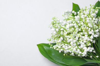 Photo of Beautiful lily of the valley flowers on light grey background. Space for text