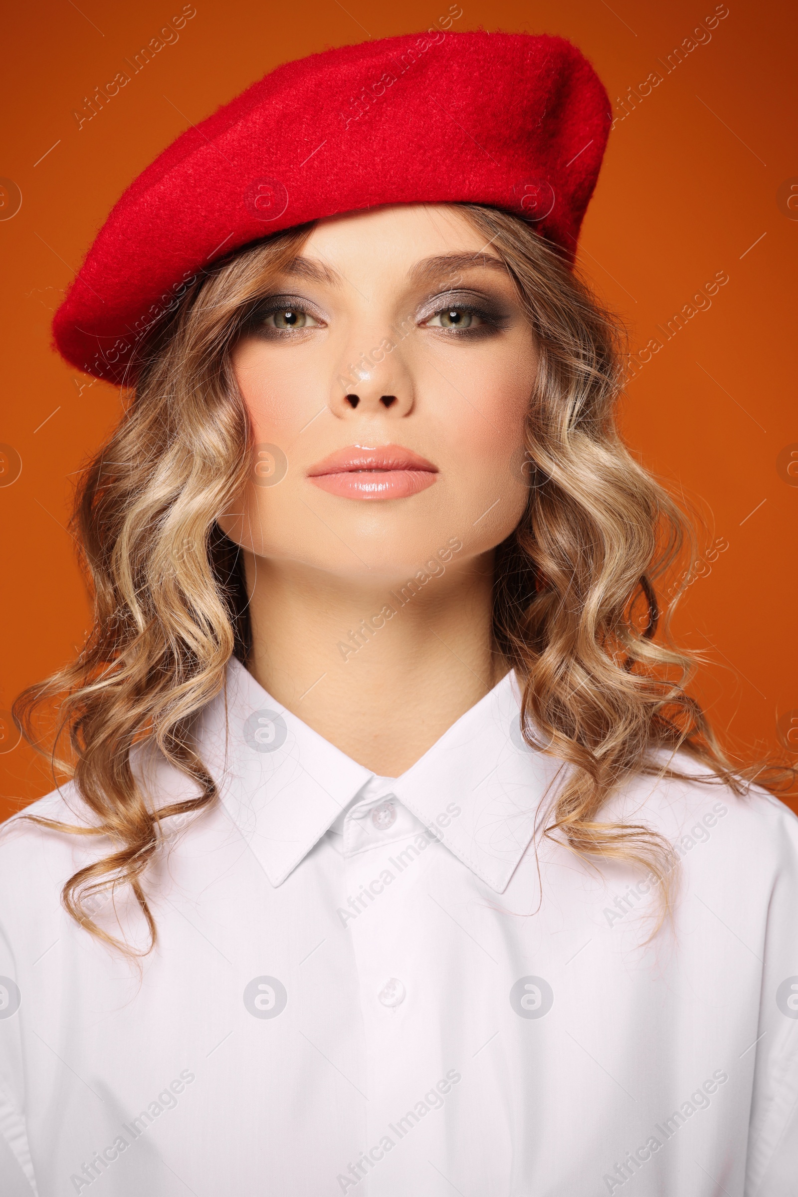 Photo of Portrait of beautiful young woman in stylish beret against orange background