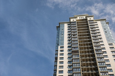 Modern building with tinted windows against sky, low angle view. Urban architecture