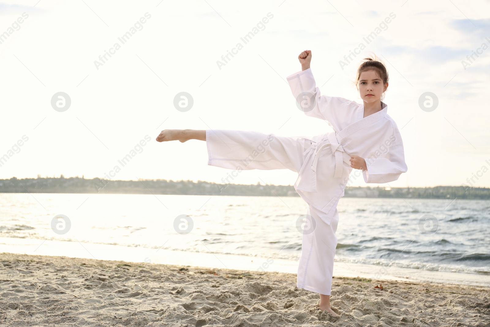 Photo of Cute little girl in kimono practicing karate near river