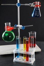 Laboratory glassware with liquids on table against black background
