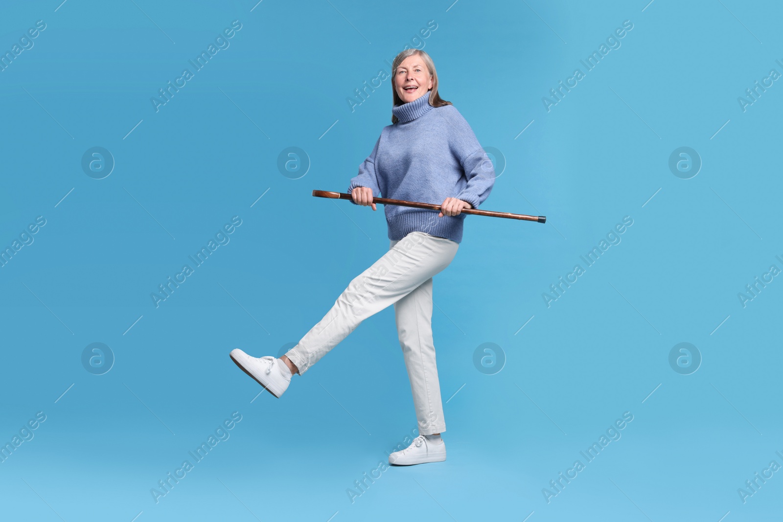 Photo of Senior woman with walking cane on light blue background