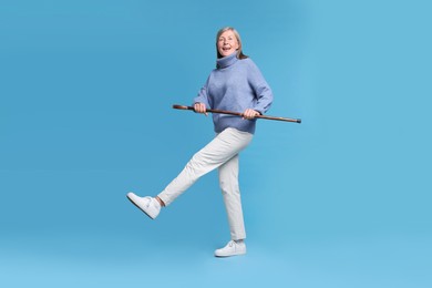 Senior woman with walking cane on light blue background