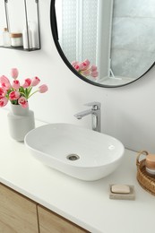 Photo of Vase with beautiful pink tulips near sink in bathroom