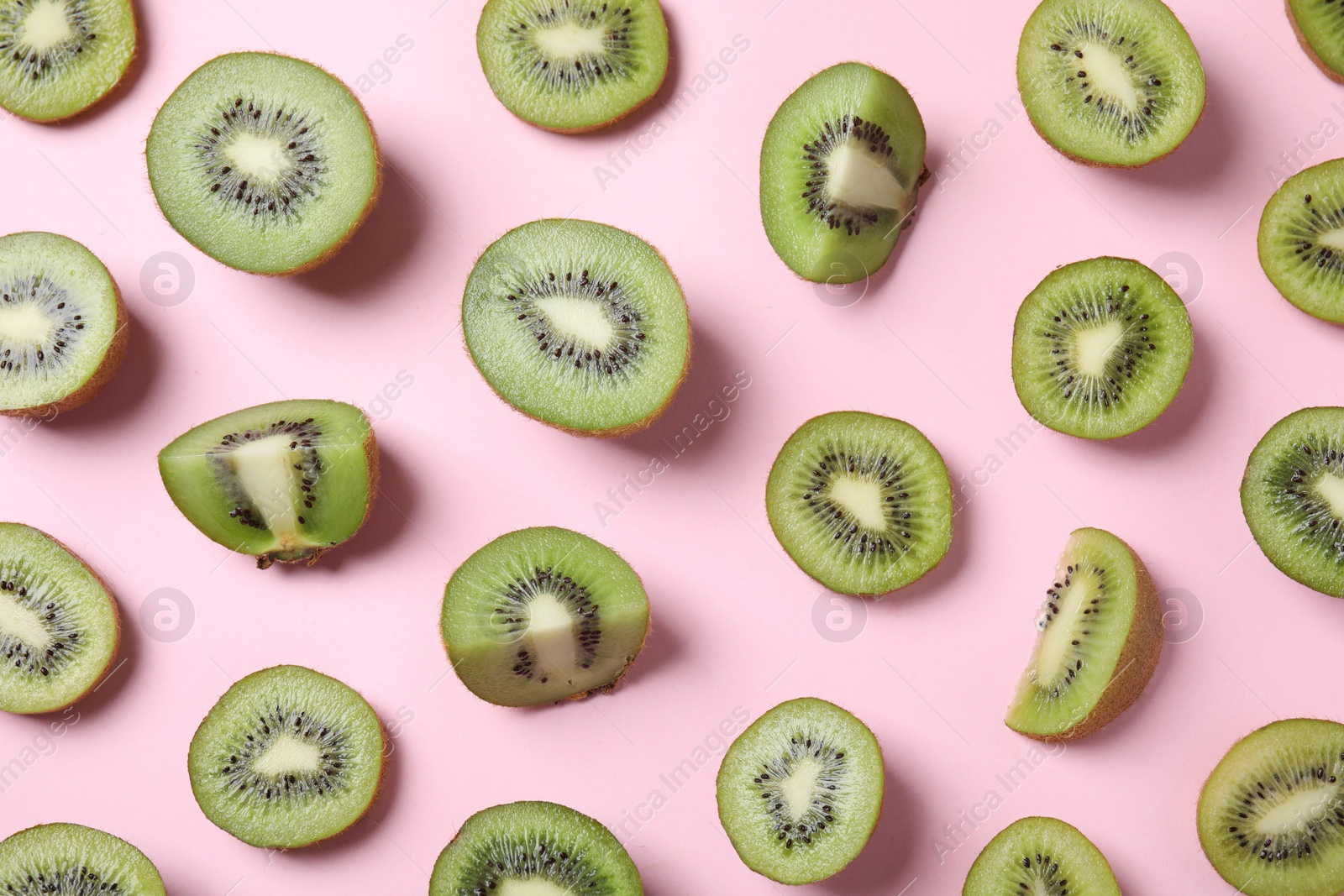 Photo of Pieces of kiwis on pink background, flat lay