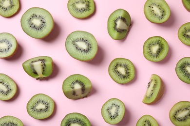 Pieces of kiwis on pink background, flat lay