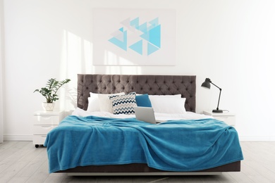 Photo of Stylish room interior with laptop on bed