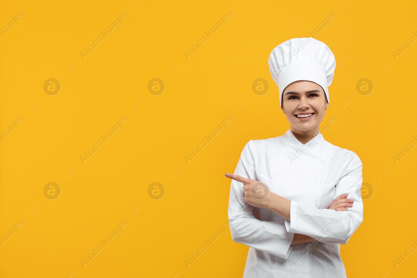 Photo of Happy female chef wearing uniform and cap on orange background. Space for text